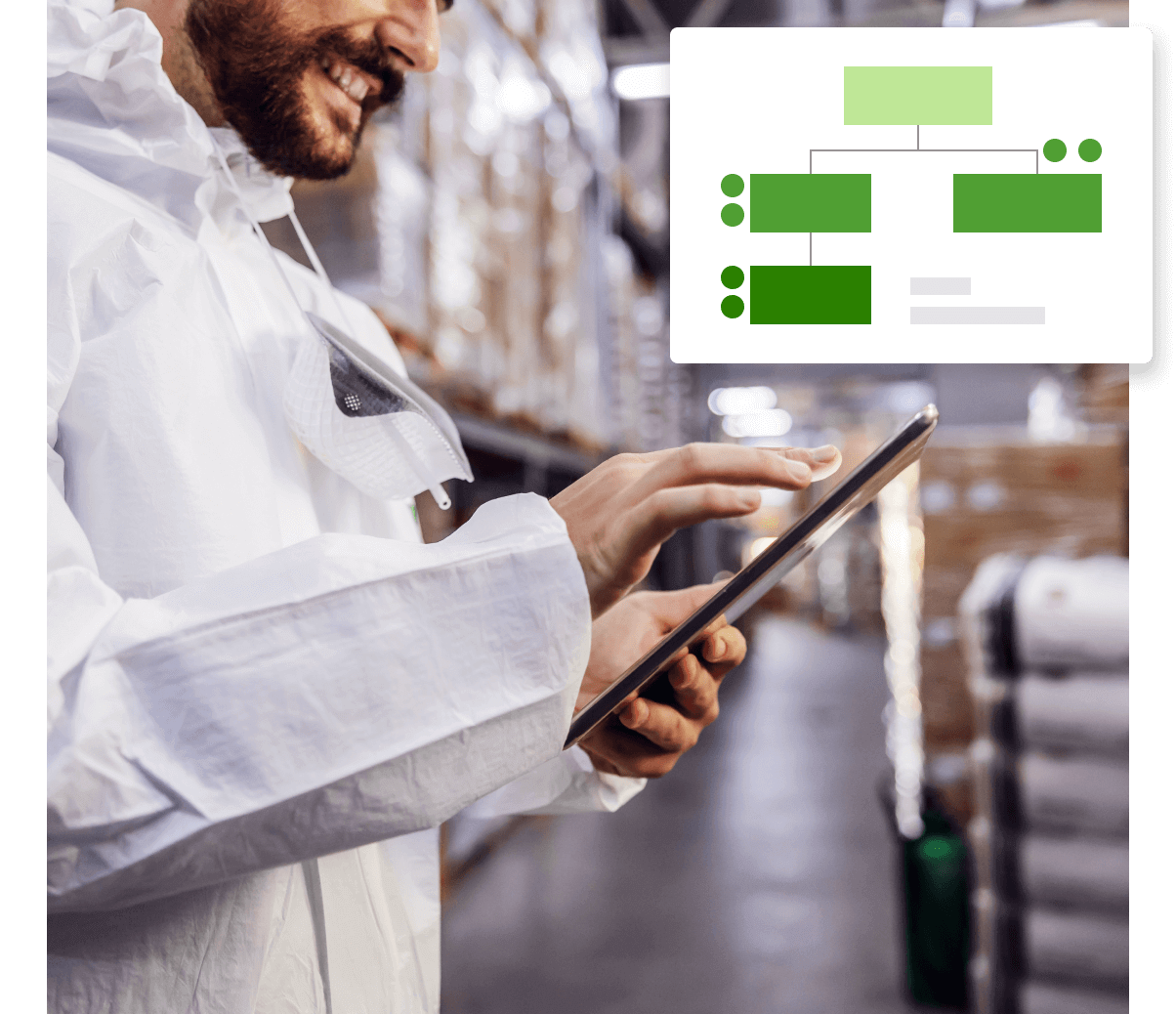 A man in a white coat is using a tablet in a warehouse.