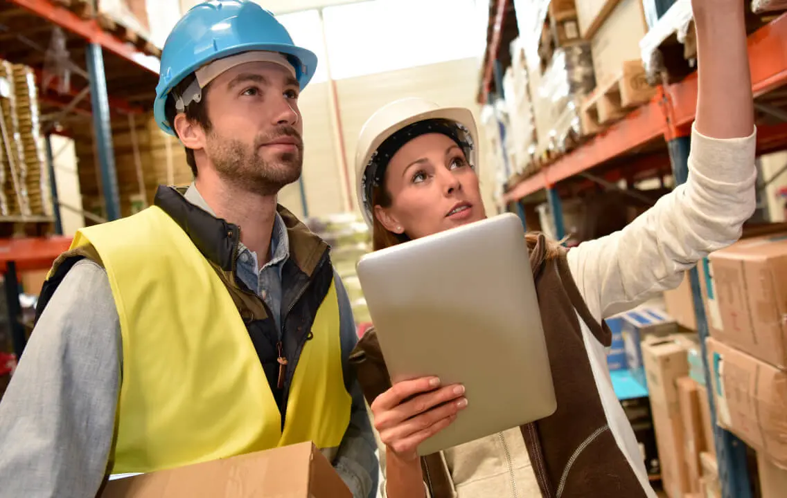 Two warehouse workers looking at a tablet in a warehouse.