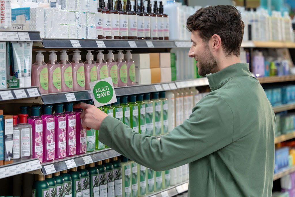 Man in a green jacket shopping for skincare products in a supermarket