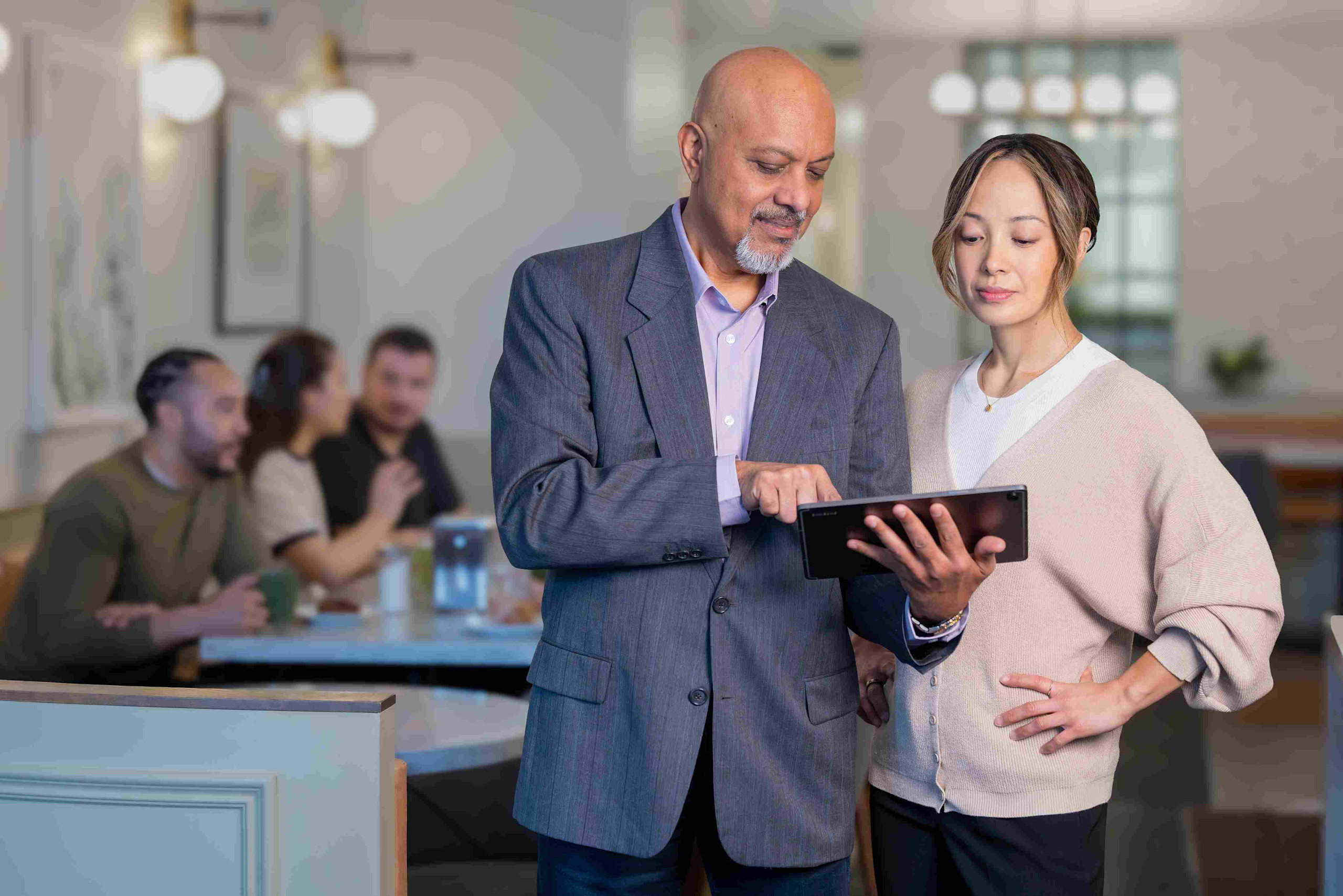 Man holding up an ipad with a lady in a restaurant