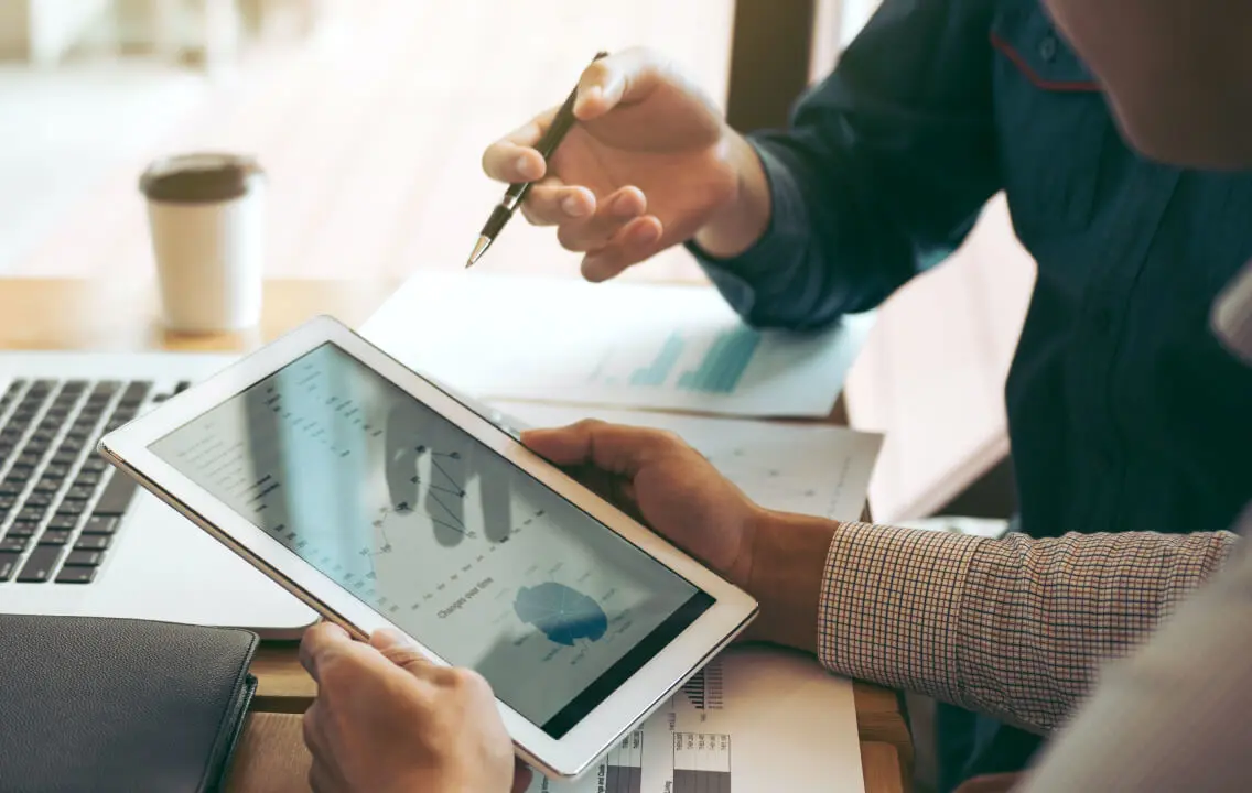 Two people sitting at a desk with a tablet