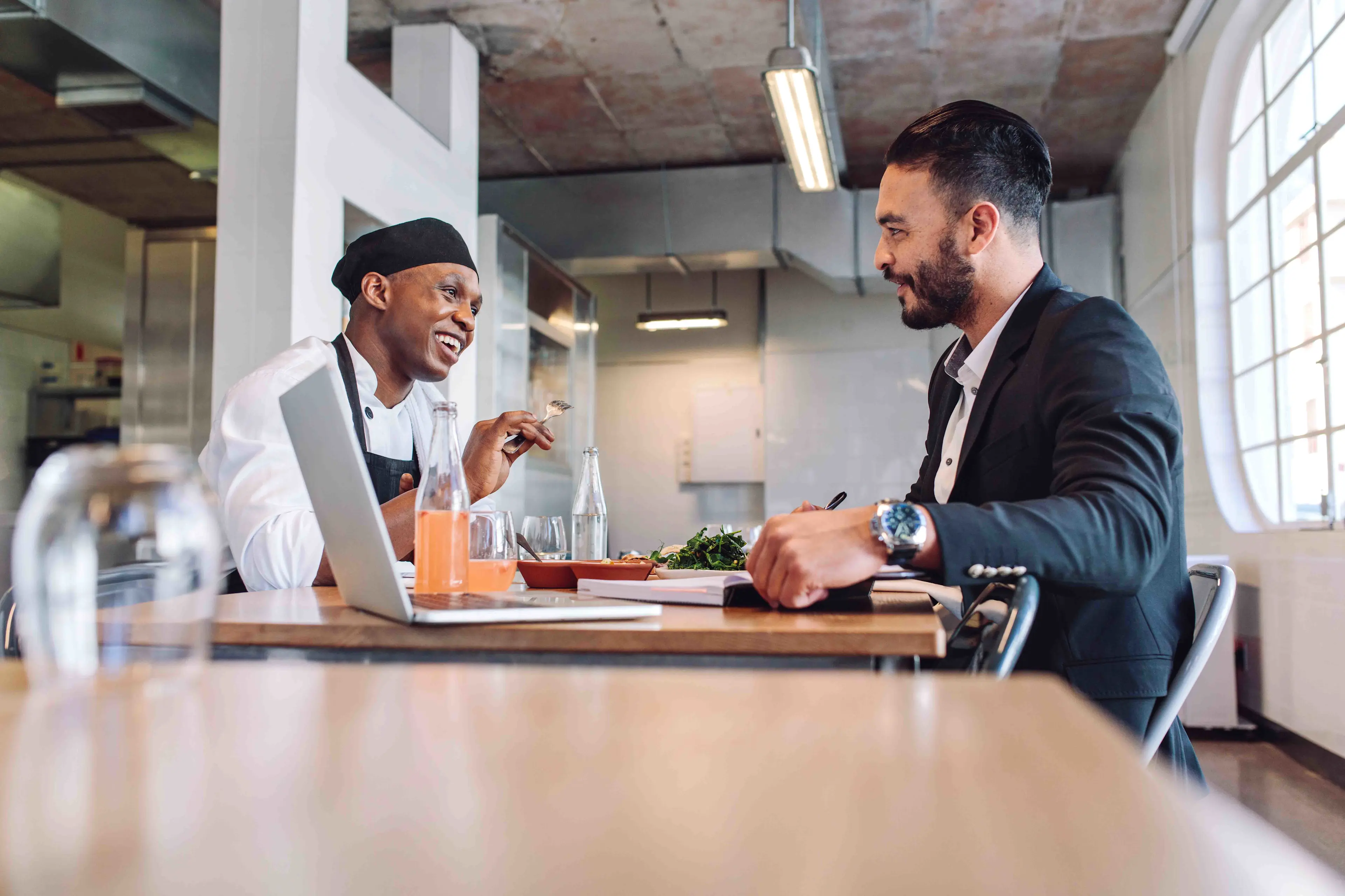 Salesperson and restaurant manager discussing sales enablement insights and sharing ideas at a restaurant table.