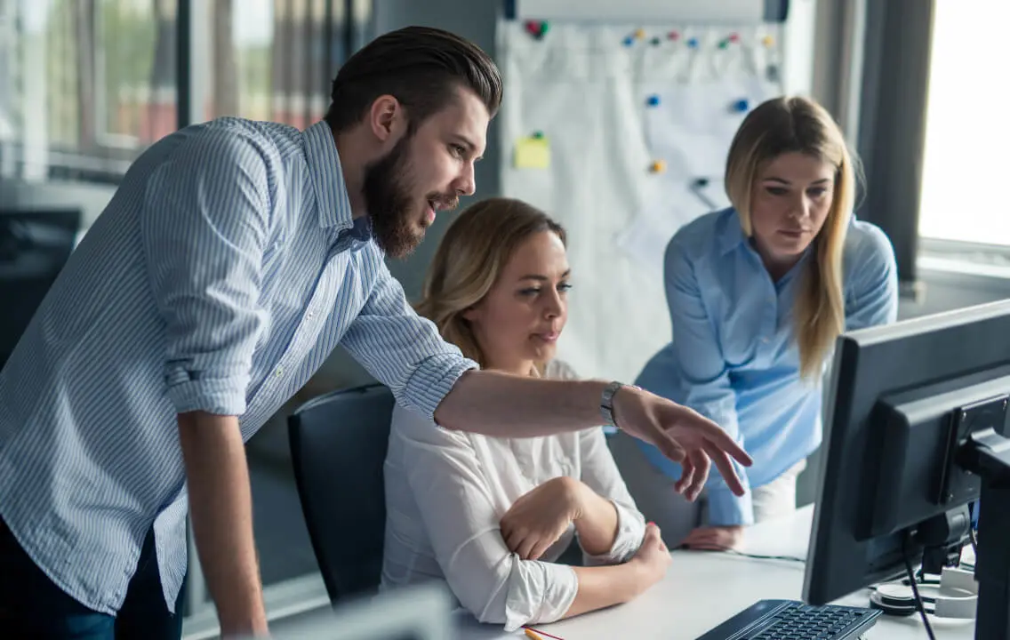 A group of people working on a computer in an office.