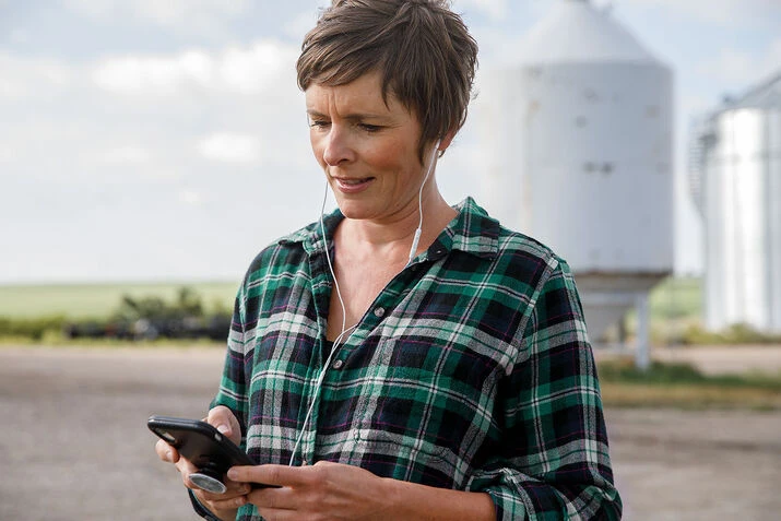 Une femme interagit avec son téléphone cellulaire, soulignant le rôle des outils numériques dans l’agriculture moderne.