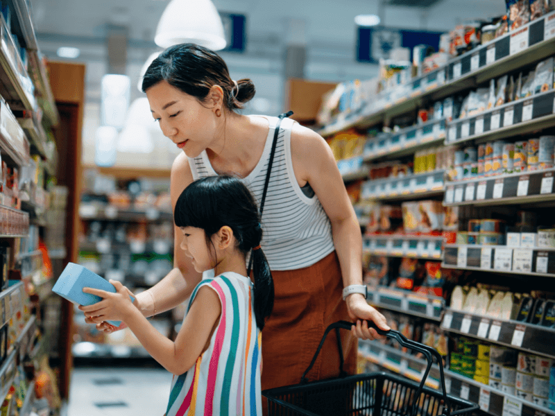 Woman shopping in store with child reviewing trade promotions 

