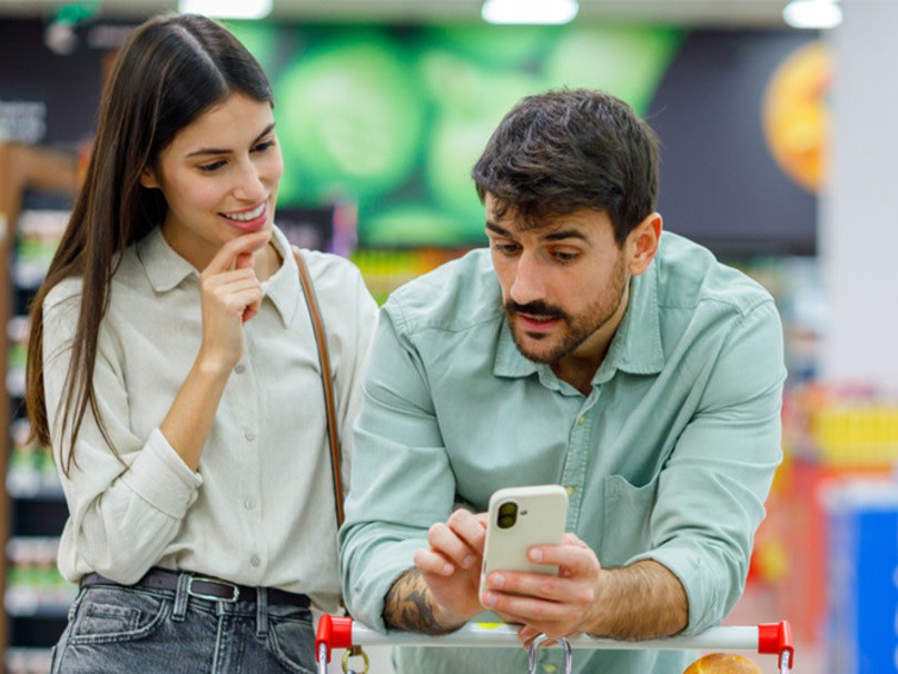 Couple shopping in grocery store and looking at phone