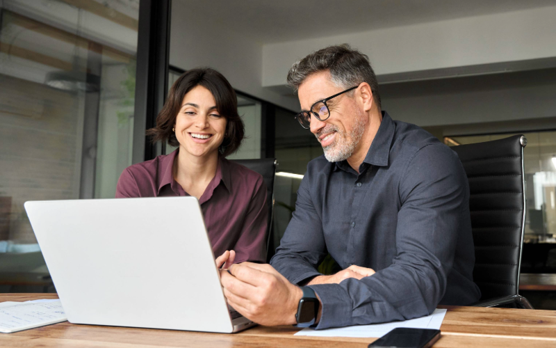 A man and a woman engage in a discussion in a meeting room focused on trade promotion management strategies