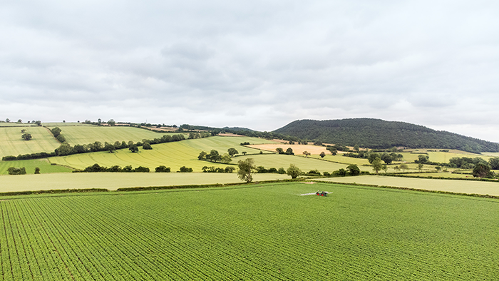Tractor in the center of a green field symbolizing farm payroll and agricultural productivity.