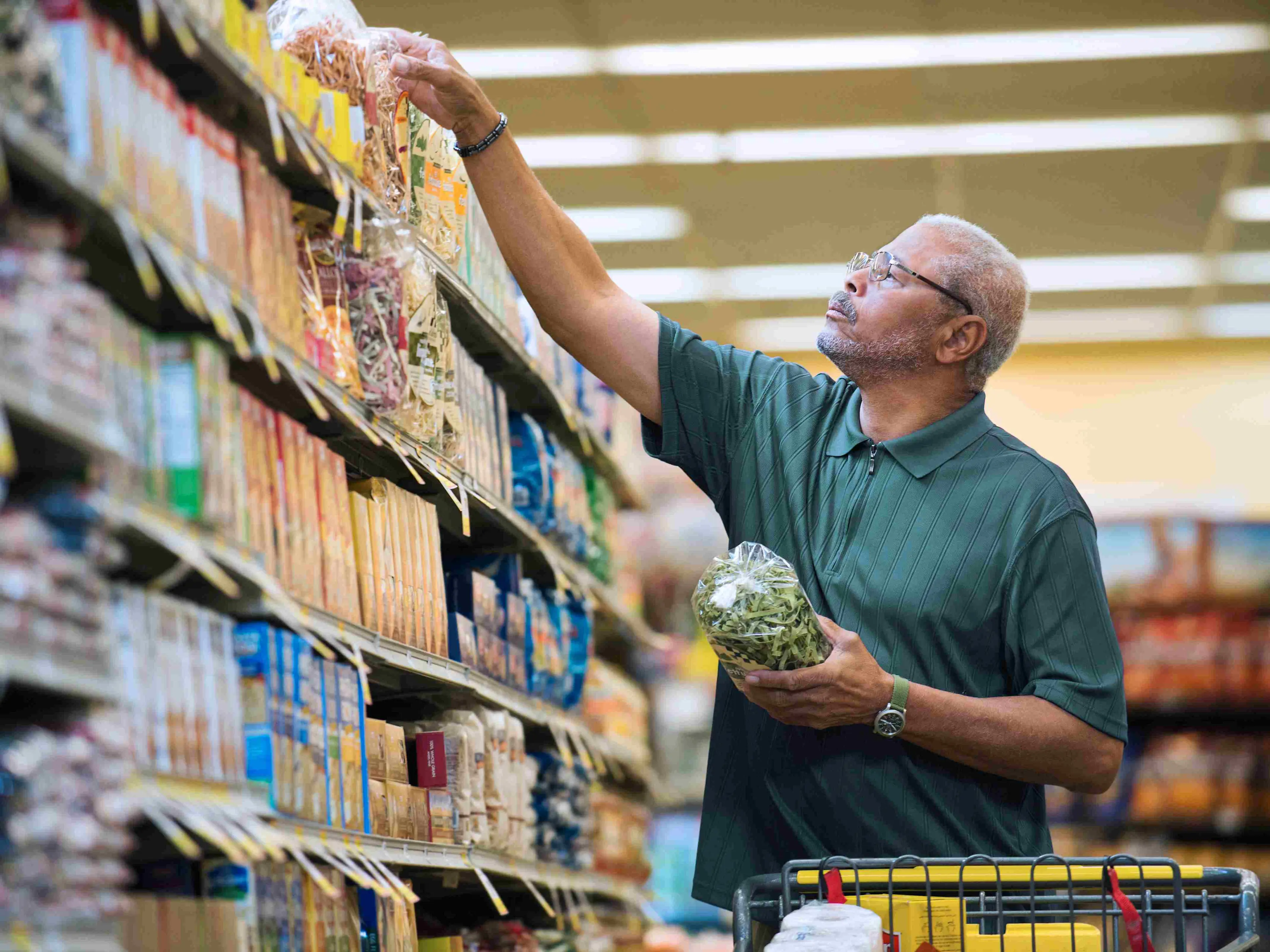Man chooses product from a retail shelf with organized CPG products in planogram arrangement

