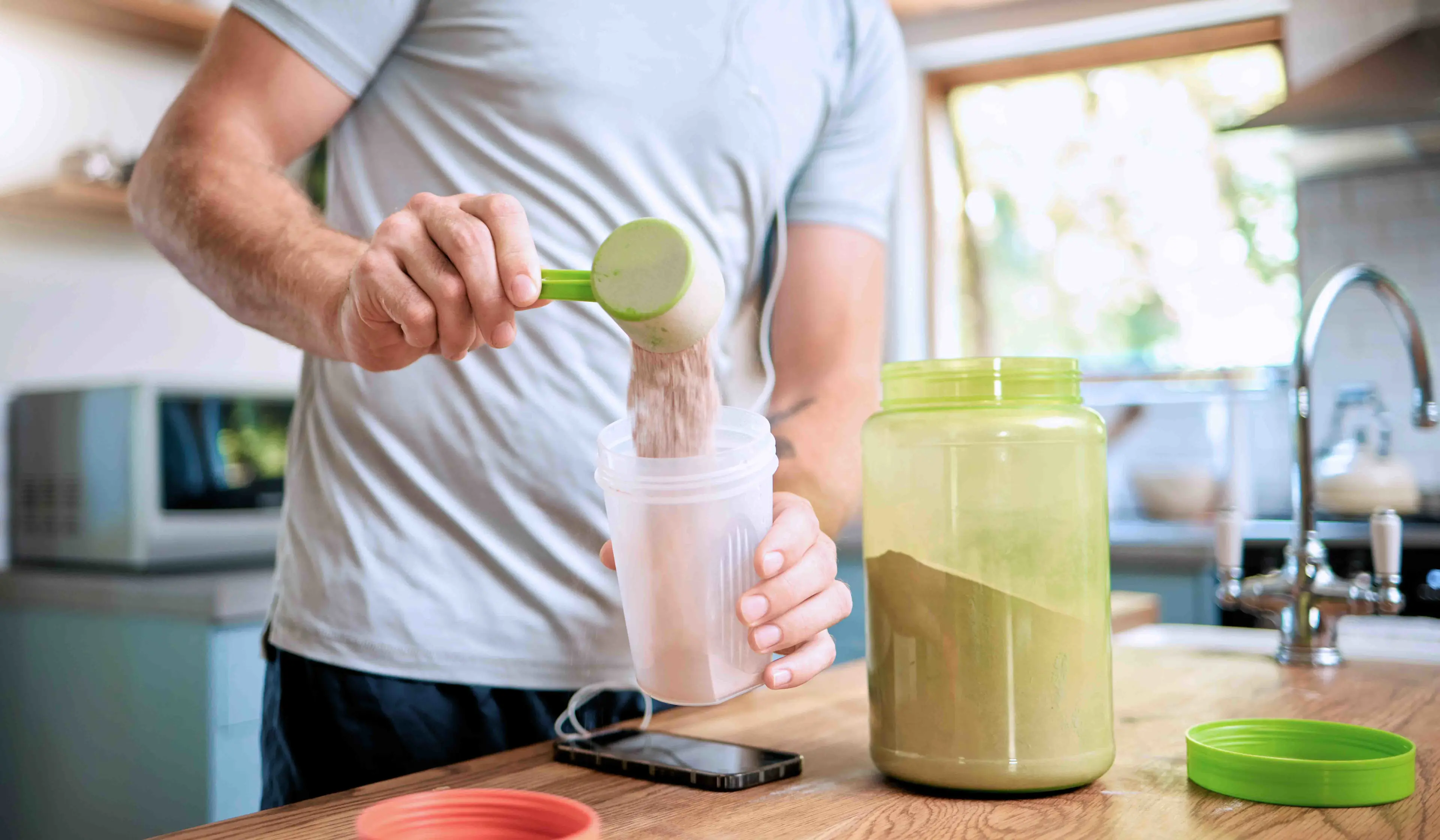 A man pours a thick shake into a blender, preparing to mix the ingredients for a smoothie.