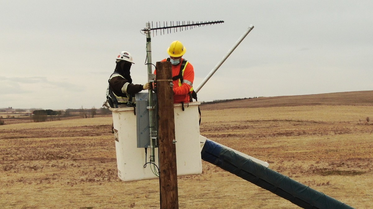 TELUS technicians install the repeater on the Olds College Smart Farm.
