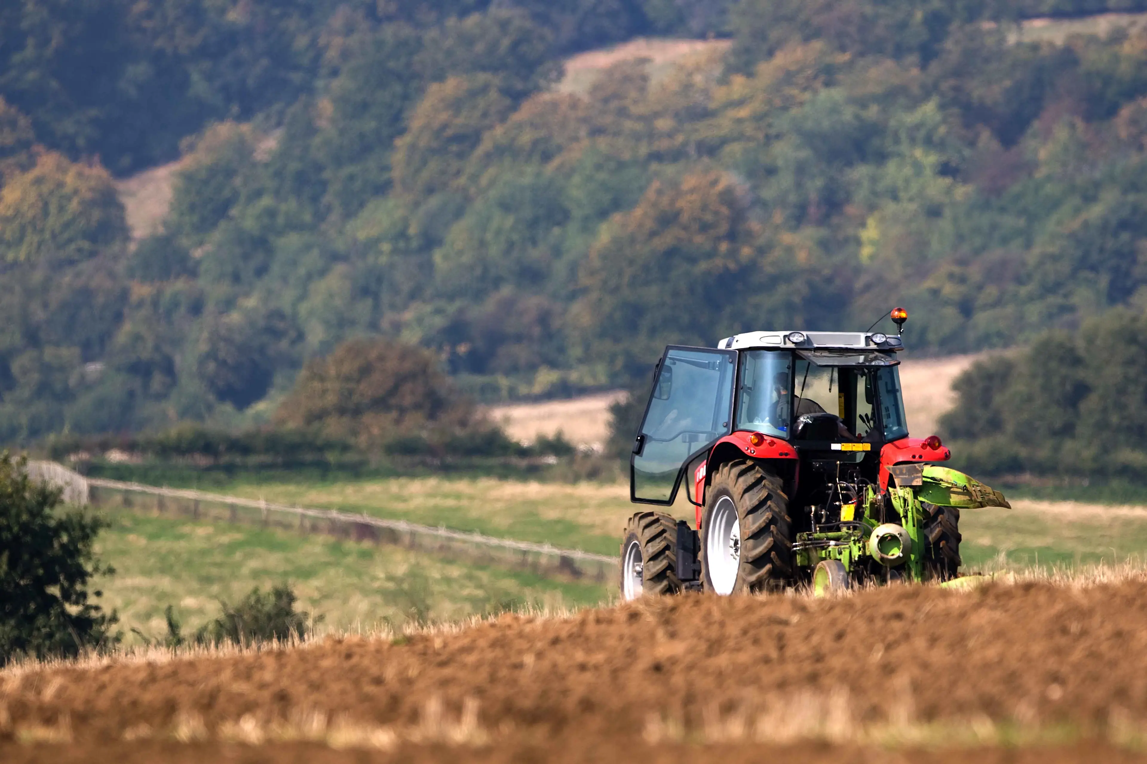 A US farmer tending to his crops with a red tractor

