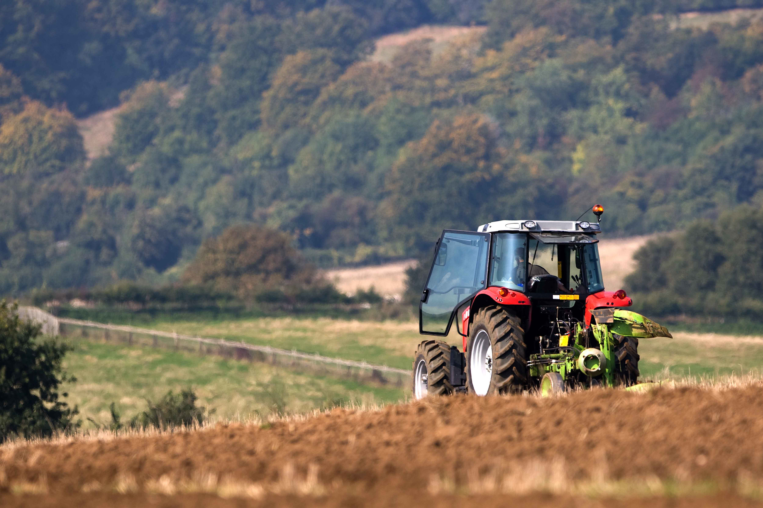 A US farmer tending to his crops with a red tractor

