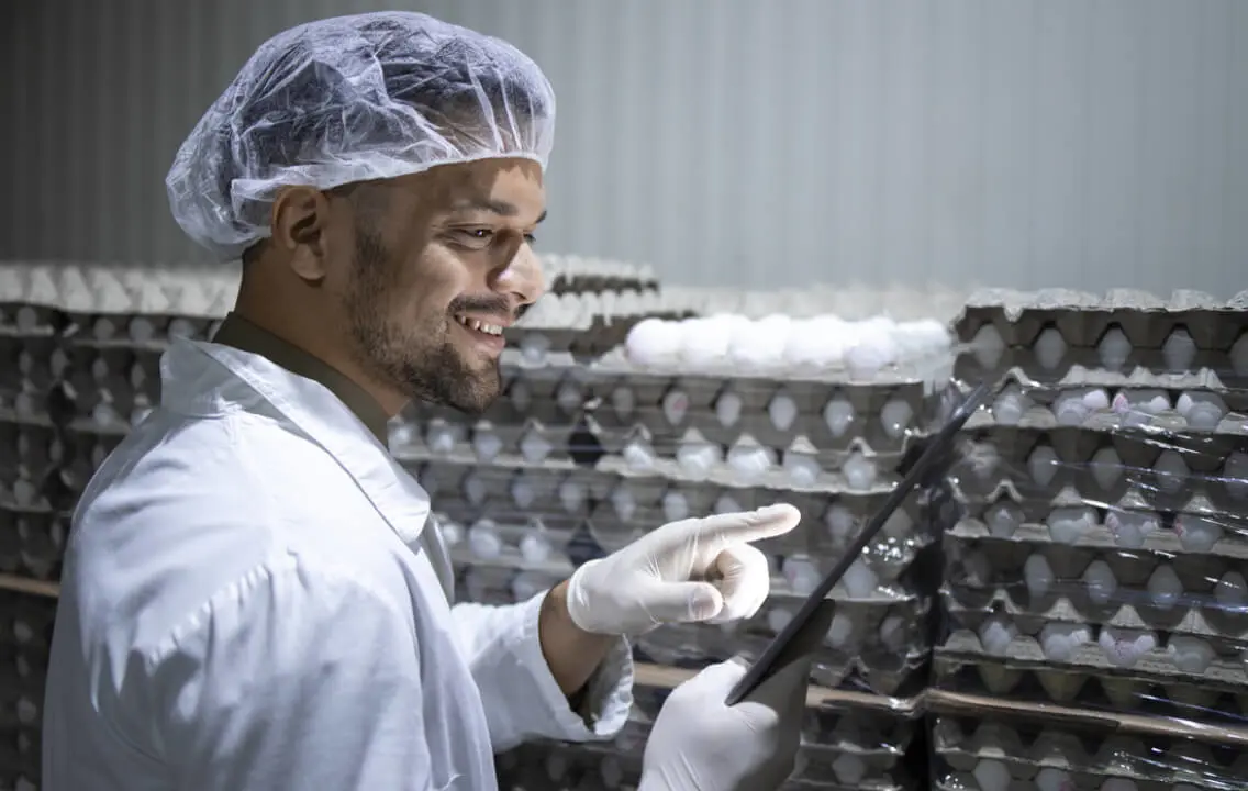 A man in a lab coat is holding a tablet.