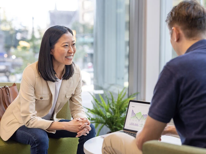 A woman and man engage in a discussion in a meeting room focused on Trade Promotion Management strategies.