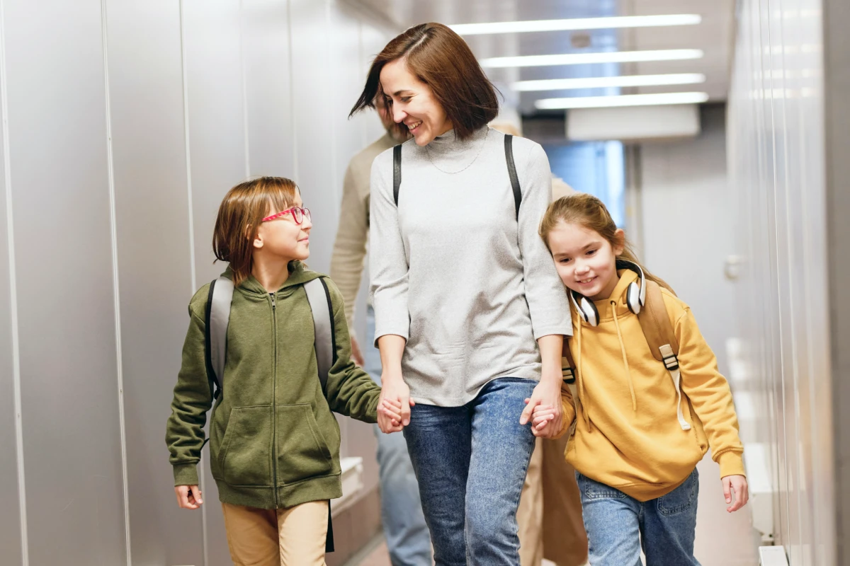 A parent walking through the airport with two children