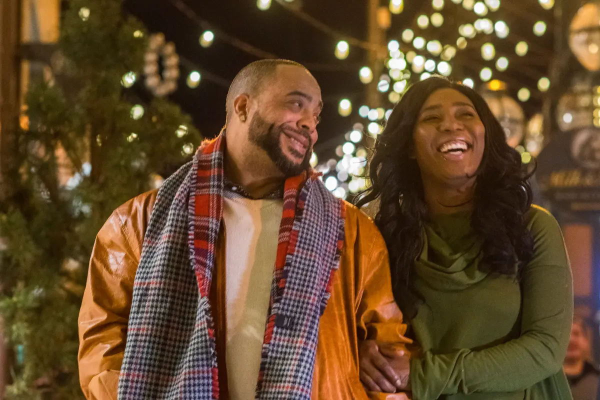 A couple laughing and smiling with fairy lights in the background