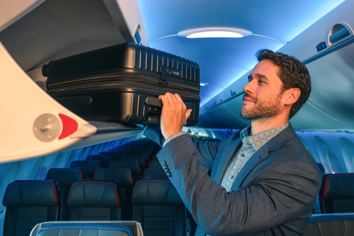 A Guest placing a carry-on bag in the overhead bin