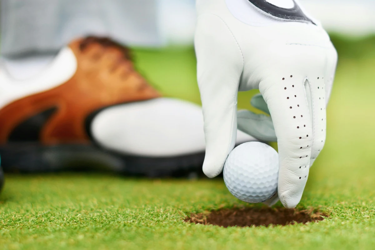 A golfer pulling the ball from the hole