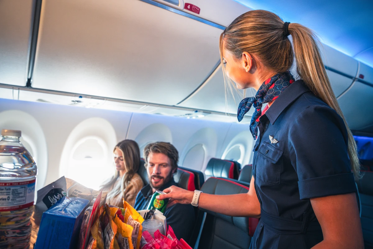 A Breeze Airways flight attendant serving snacks onboard