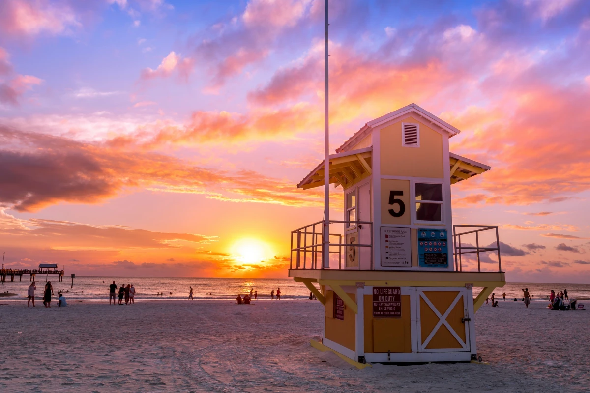 A sunset on a sandy beach with a lifeguard tower