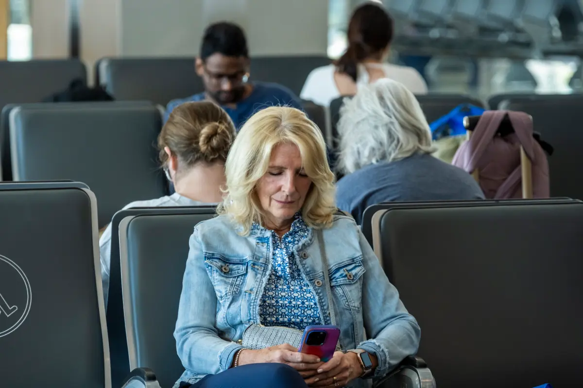 A woman sitting in an airport looking at her phone