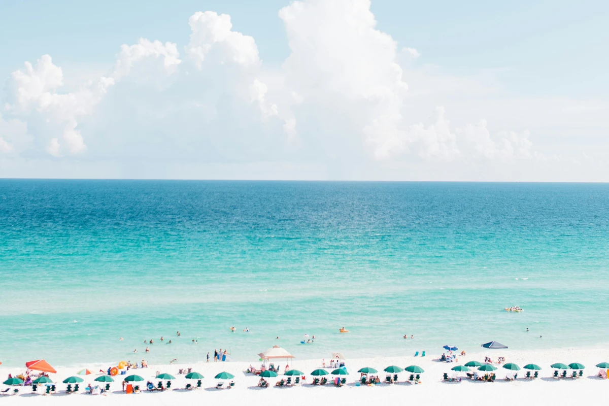 Beachgoers sitting on white sand overlooking turquoise waters