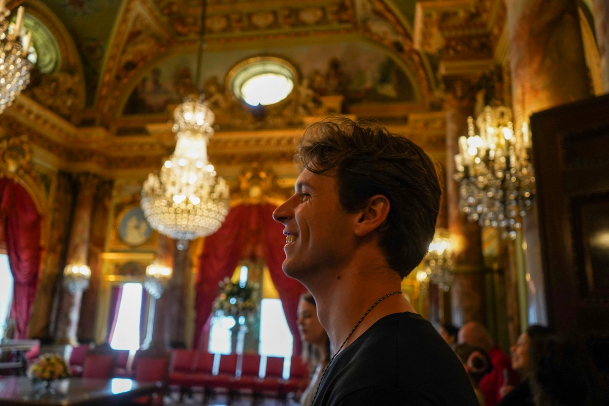 Bru smiling in a decorated building with chandeliers