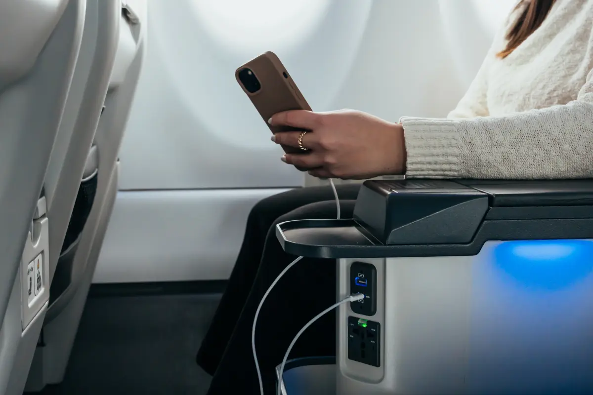 A person sitting on an airplane and looking at their phone