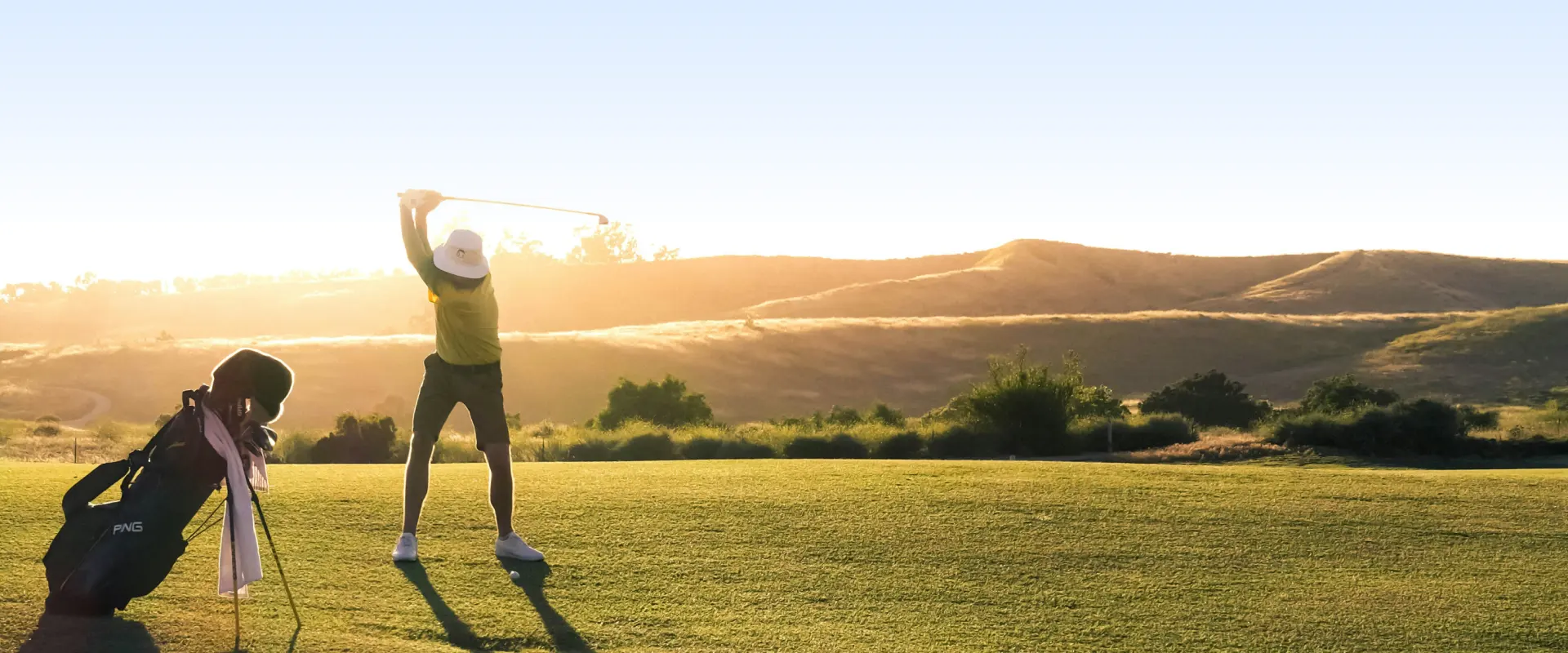 Golf course fairway at sunset with rolling greens