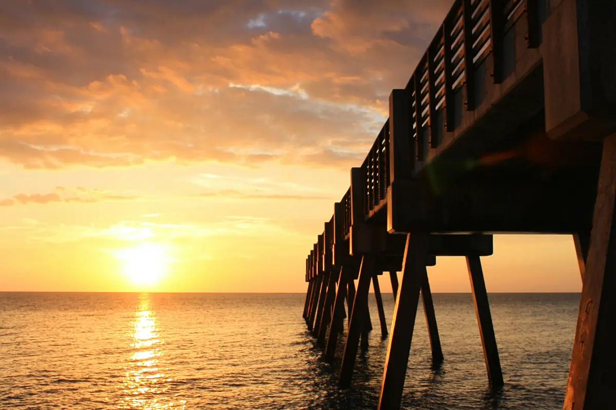 A sunrise over the ocean next to a boardwalk