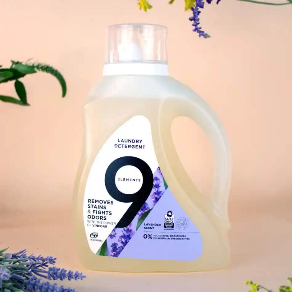 9 Elements lavender laundry detergent bottle with flowers and citruses around.