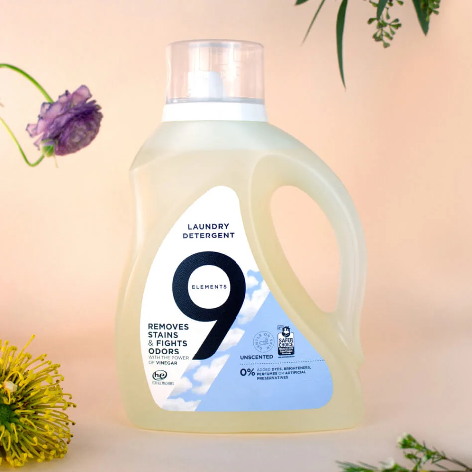 9 Elements unscented laundry detergent bottle surrounded by various plants