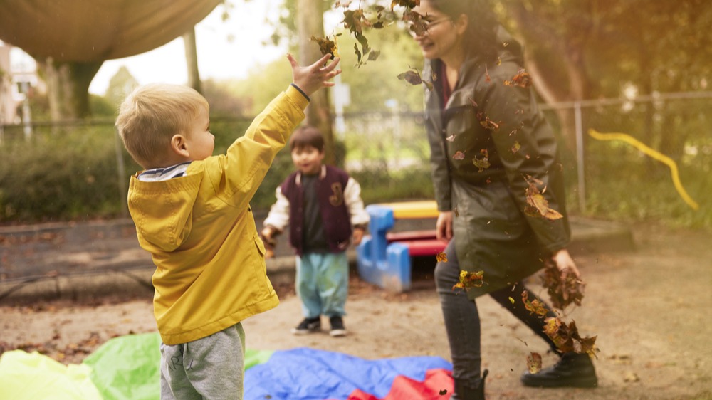 pedagogisch professional met kinderen spelen buiten met bladeren