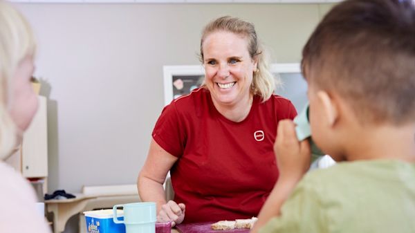 pedagogisch medewerker met kinderen aan tafel eten
