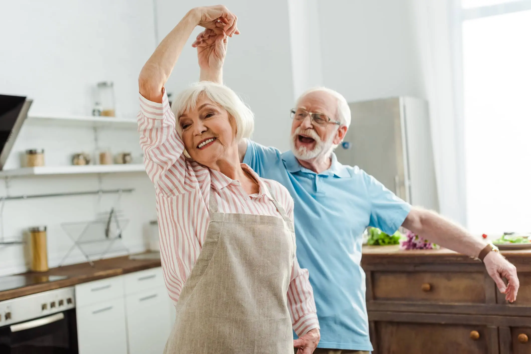 An elderly couple dances carefree in their own home, having taken care of the affordability of their mortgage in old age at an early stage 