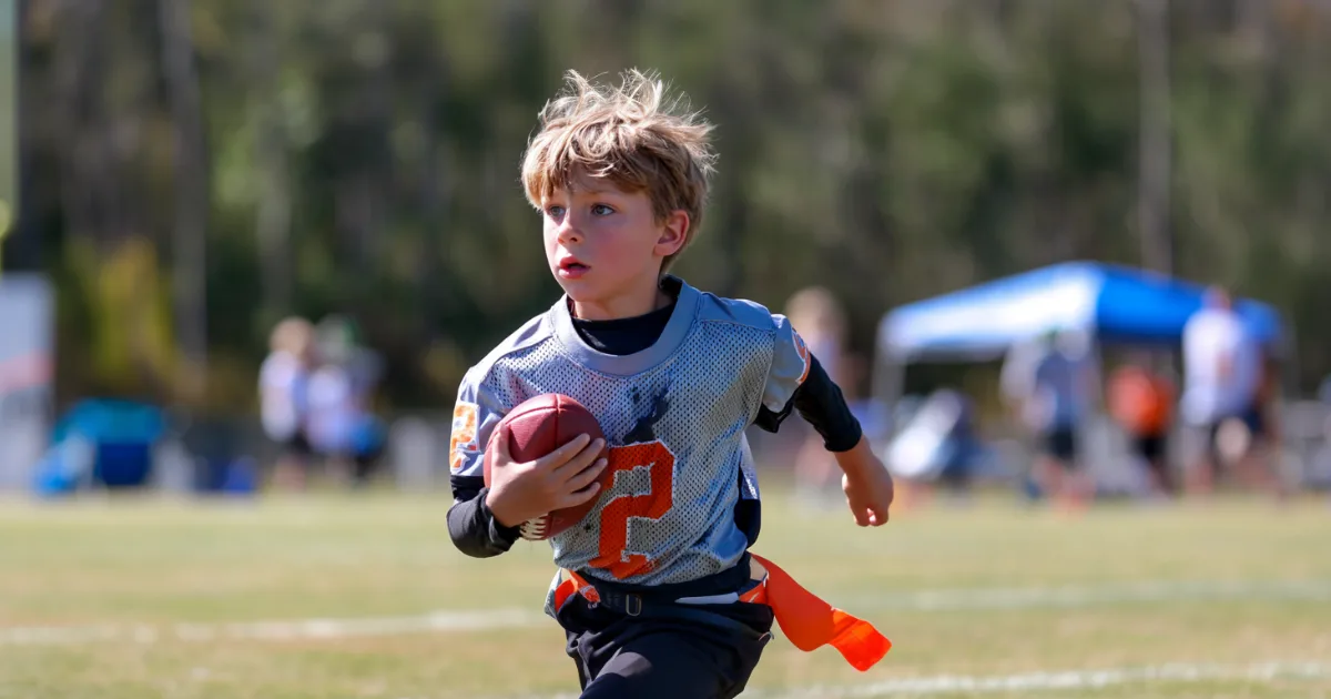A youth flag football player during a game holding a football