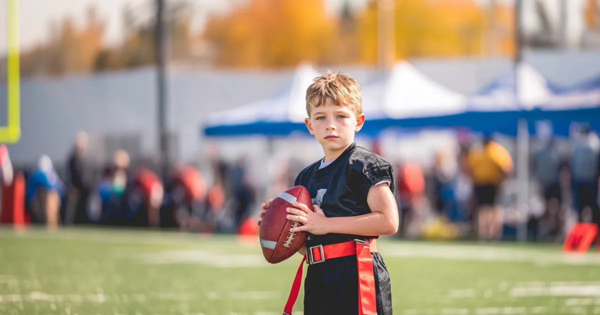 A youth flag football player holding a football during a game