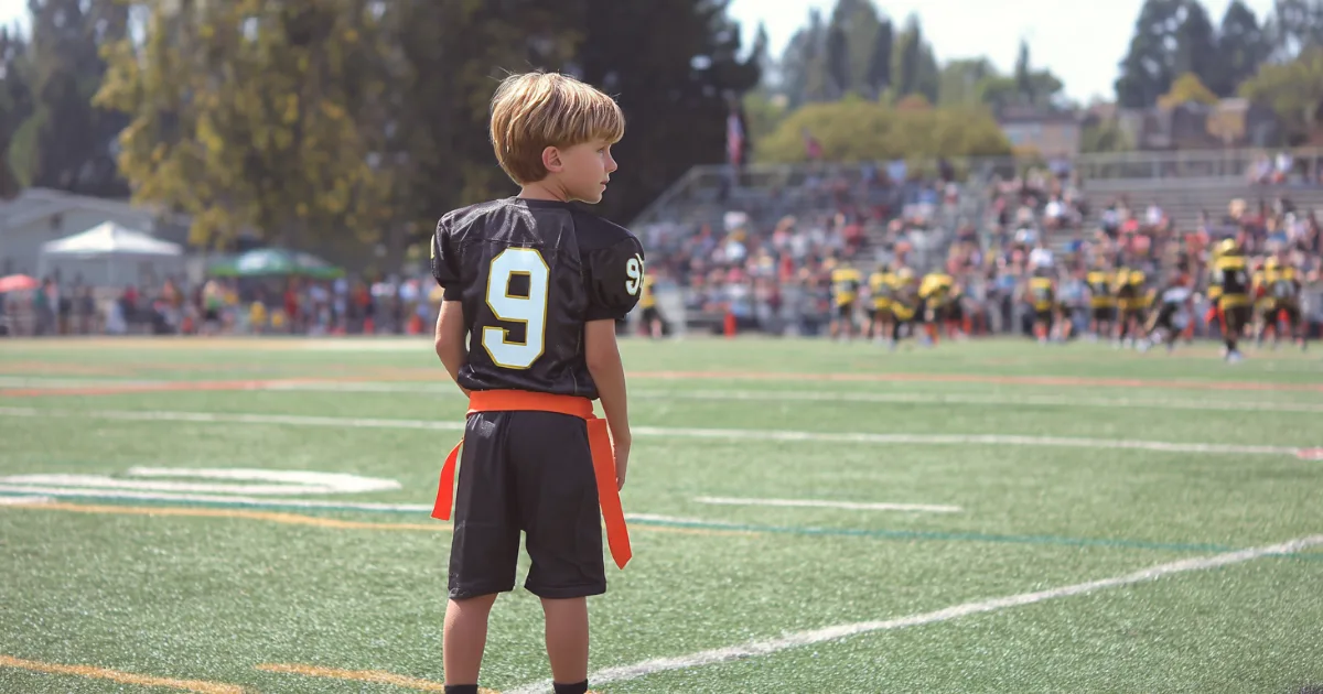A youth flag football player holding a football during a game