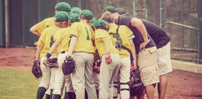 a youth baseball team and coaches huddling before a game