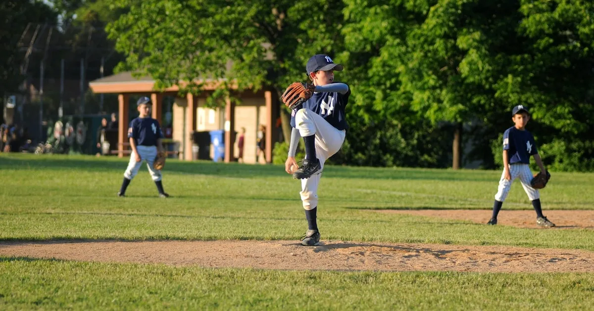a youth baseball pitcher in a wind up about to strike out a batter