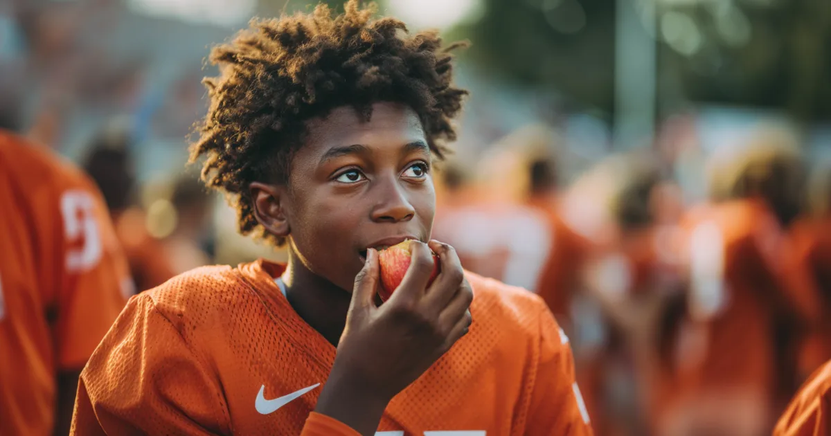 A youth sports athlete eating a healthy snack during a game