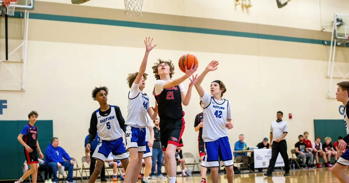 Youth basketball players in a game trying to stop someone from scoring