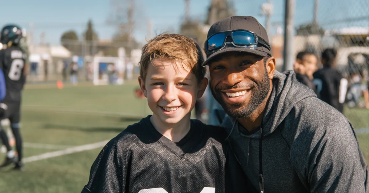 Youth sports volunteer coach with a young football player smiling for a photo