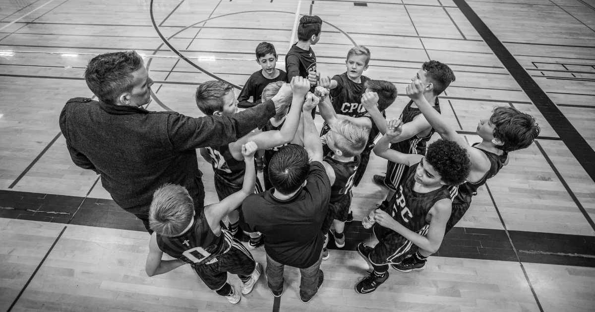 A youth sports coach with his basketball players in a huddle