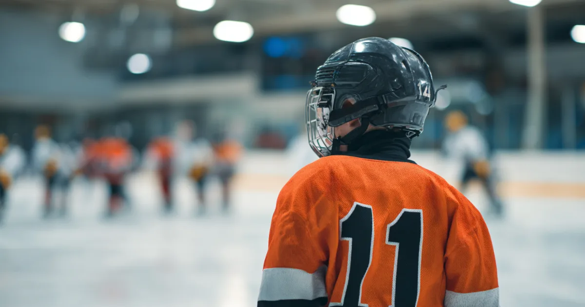 a youth hockey player getting ready to go on the ice before a game