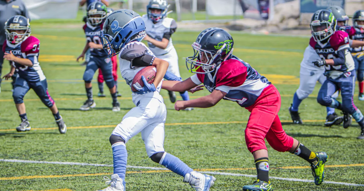 A youth football player carrying a football during the game