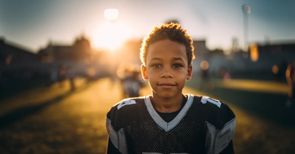 A youth football player smiling at the camera after a game