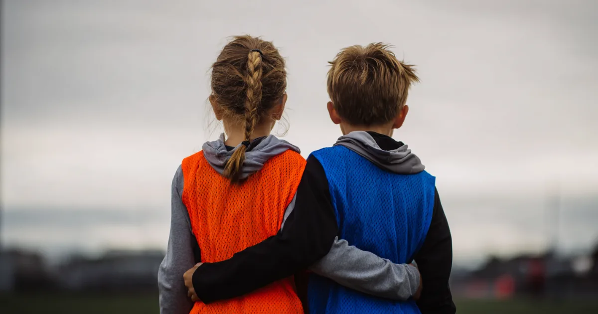 Two youth sports players standing beside each other before a practice