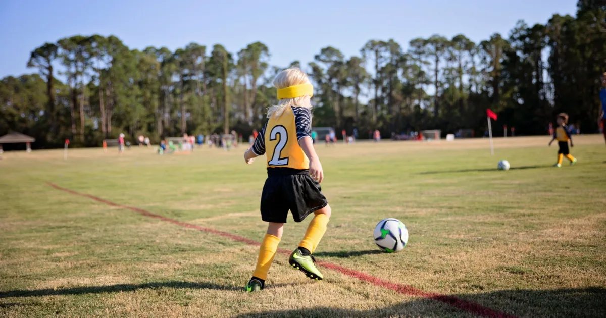 A youth soccer player kicking a ball during a game